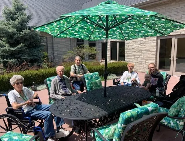 A big group of seniors sitting around a table outside in the garden